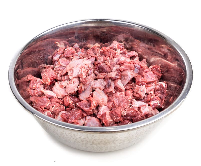 Bol en inox rempli de morceaux de viande crue coupée, illustrant les bases du régime BARF pour l'alimentation du Golden Retriever